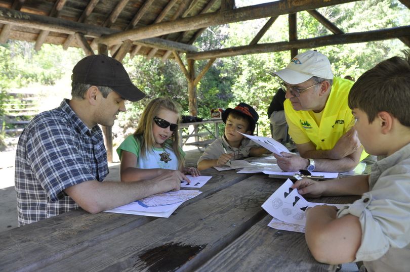 John Beck of the Eastern Washington Orienteering club, in yellow, teaches a family how to read an orienteering map.   (Rich Landers)