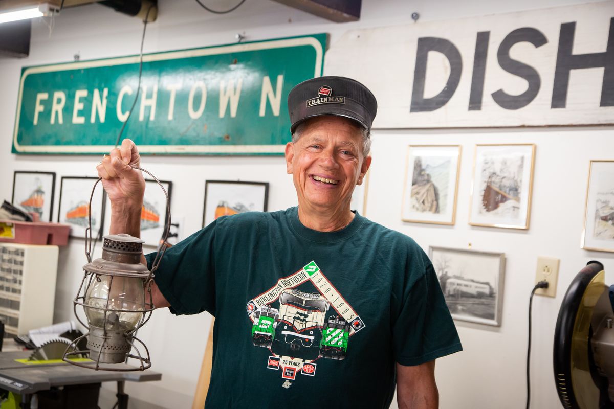 Craig Smith dons a Burlington Northern commemorative T-shirt, a trainman hat and holds up a railroad lantern in the basement of his home in rural Spokane where he is building a model railway.  (Libby Kamrowski/THE SPOKESMAN-REVIEW)