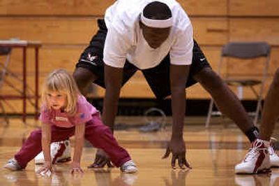 
Megan Christianson-Pinh stretches out with Eastern Washington University's Khary Nicholas in Reese Court on Sunday during the first of four sessions for the Eager Eagles Basketball Clinic. 
 (Liz Kishimoto / The Spokesman-Review)