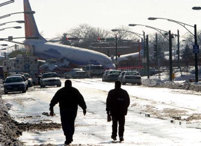 
Residents walk near a Southwest Airlines 737 on Friday that slid off a Midway Airport runway in Chicago on Thursday. 
 (Associated Press / The Spokesman-Review)