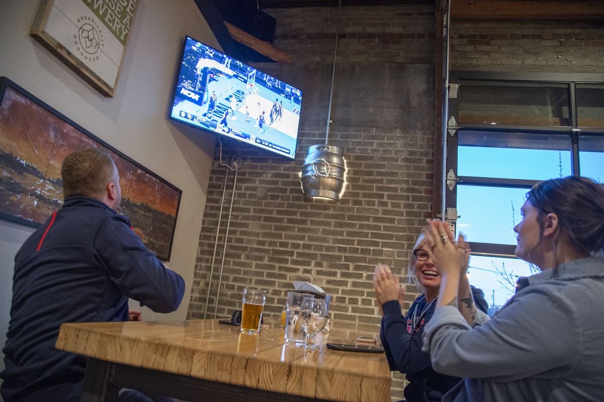 Brendan Neeson, Kelly Rao and Kaylin Hoggle cheer a GU play early in the big game at the Hidden Mother Brewery taproom in North Spokane Monday, April 5, 2021 though the Gonzaga Bulldogs came up short against the Baylor Bears in the NCAA national championship game.  (Jesse Tinsley/The Spokesman-Review)