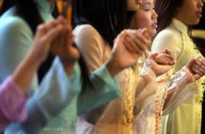 
Lanchi Pham, 19, prays with her Vietnamese dance group after they performed a traditional prayer dance at St. Joseph's Parish at the Thanksgiving Day Mass. 
 (Jed Conklin / The Spokesman-Review)