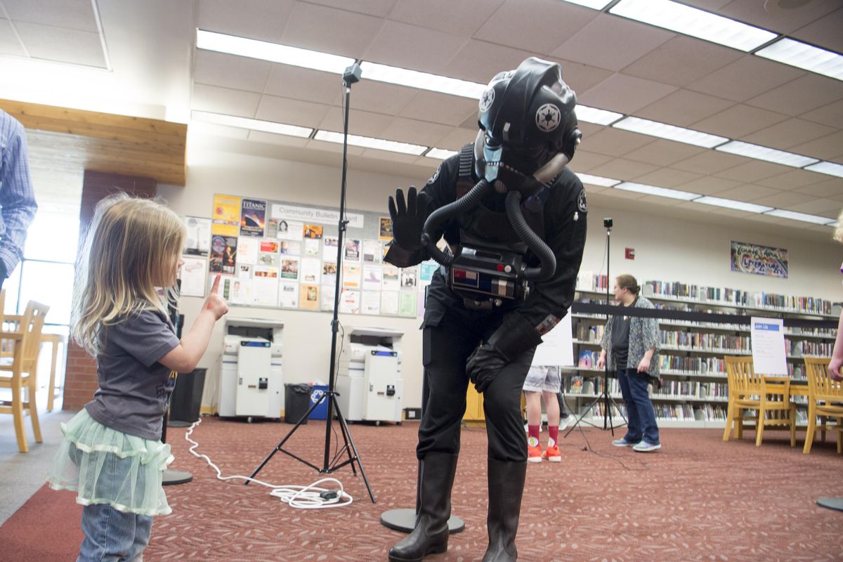At Library Con, a comic book convention at the Spokane Public Library South Hill location, Theodora Jaynes, 4, shyly waves at a Star Wars enthusiast who was dressed as a Tie Fighter pilot for the event Saturday, May 5, 2018. The event drew comic book readers, artists, costume enthusiasts and others. Changes may be in store for the South Hill branch as library planners propose moving the small neighborhood library in order to allow expansion. The current library is at Perry St. and 34th Ave. (Jesse Tinsley / The Spokesman-Review)