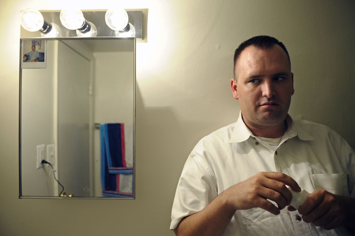 In this Aug. 23, 2012 photo, Kevin Earley, 33, holds a bottle of his antipsychotic medication as he stands next to the medicine cabinet which has an old photo taped to it, in the bathroom of his Vienna, Va., apartment that he shares with a roommate. Of the photo, Earley says, "It reminds me to take my medicine every day and reminds me of where I have been and what I have been through." (Cliff Owen / Fr170079 Ap)