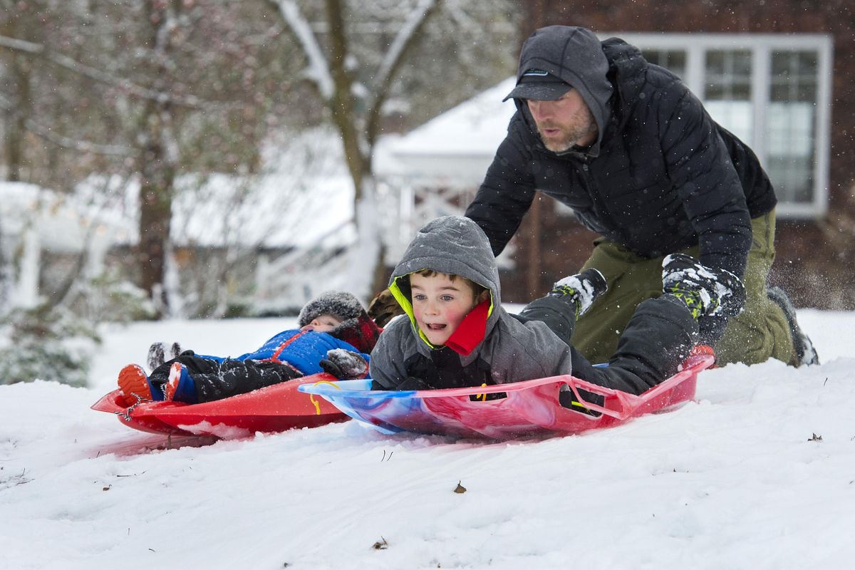 Mike Dewey launches his sons Boone, left and Nash, on their new sleds, Monday, Dec. 25, 2017, at Cannon Hill Park. The boys received the red sled, left, on Christmas morning and other a few day ago. (Dan Pelle / The Spokesman-Review)