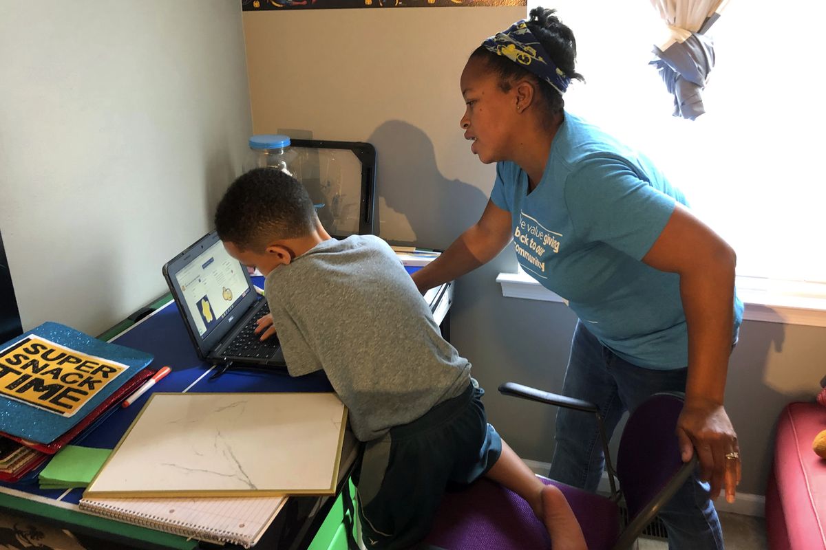Tiffany Shelton helps her 7-year-old son, P.J. Shelton, a second-grader, during an online class on Sept. 3 at their home in Norristown, Pa.  (Michael Rubinkam)