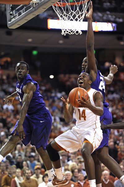 Texas guard J'Covan Brown, front, fights past Kansas State forward Curtis Kelly, rear, and guard Martavious Irving, left. (Associated Press)