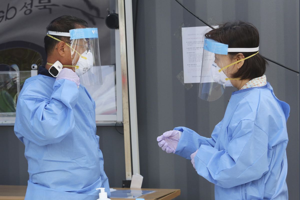 A medical worker measures his own body temperature during the COVID-19 testing at a makeshift clinic in Seoul, South Korea, Wednesday, Aug. 26, 2020. Health officials in South Korea called on thousands of striking doctors to return to work as the country counted its 13th straight day of triple-digit daily jumps in coronavirus cases.  (Ahn Young-joon)