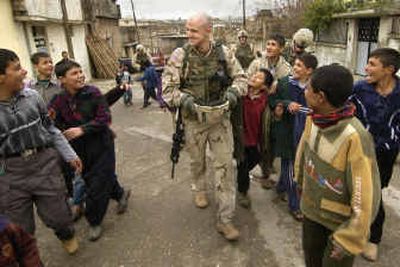 
U.S. Army 1st Battalion, 24th Infantry Regiment Lt. Raub Nash shows off his shaved head to boys Saturday in Mosul, Iraq. After last Sunday's elections in Iraq, some troops said they felt better about their role there. 