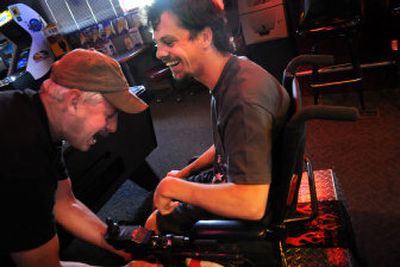 
Skills Center teacher Dan Horton fixes a broken light on K.C Chapman's wheelchair at Illinois Avenue Bar and Grill in Spokane on June 19.  
 (Rajah Bose / The Spokesman-Review)