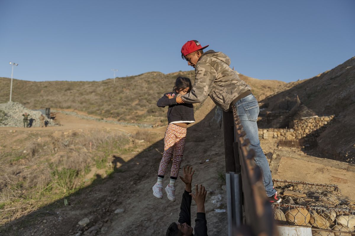 FILE - In this Jan. 3, 2019, file photo, a migrant from Honduras pass a child to her father after he jumped the border fence to get into the U.S. side to San Diego, Calif., from Tijuana, Mexico. As of this week, the ACLU has filed nearly 400 lawsuits and other legal actions against the Trump administration, some meeting with setbacks but many resulting in important victories. Of the lawsuits, 174 have dealt with immigrant rights, targeting the family separation policy, detention and deportation practices, and the administration’s repeated attempts to make it harder to seek asylum at the U.S.-Mexico border. (Daniel Ochoa de Olza)