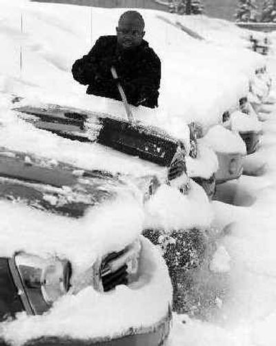 
Ernest Bolden, a sales consultant at Meade Dodge in Detroit, clears snow off a Dodge Durango on the sales lot Tuesday. 
 (Associated Press / The Spokesman-Review)