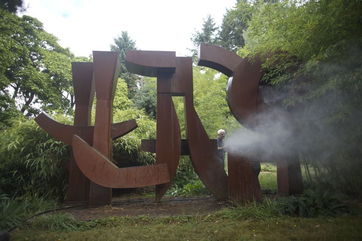 Lee Kelly in 2010 pressure-washes Memory 99, one of the pieces in his career retrospective at Portland Art Museum.  (Motoya Nakamura)