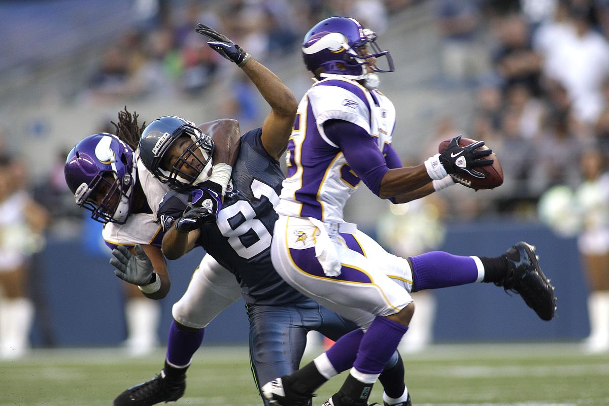 Minnesota’s Marcus Sherels intercepts a first-quarter pass as Vikings teammate E.J. Henderson, left, takes down Seattle’s Golden Tate. (Associated Press)