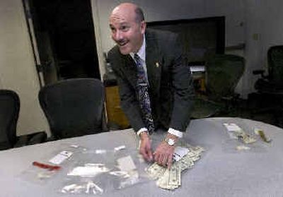 
U.S. Drug Enforcement Administration Supervisor Selby Smith displays some of crack cocaine and $25,000 that was seized in Wednesday's raid. 
 (Colin Mulvany / The Spokesman-Review)
