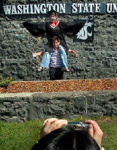 
Mari Mort sits on Michinori Hamza's shoulders as Yurie Fujsawa takes their picture Thursday in front of the Washington State University sign at the bottom of Stadium Way in Pullman. Mort is graduating with a degree in communication today. 
 (Joe Barrentine / The Spokesman-Review)