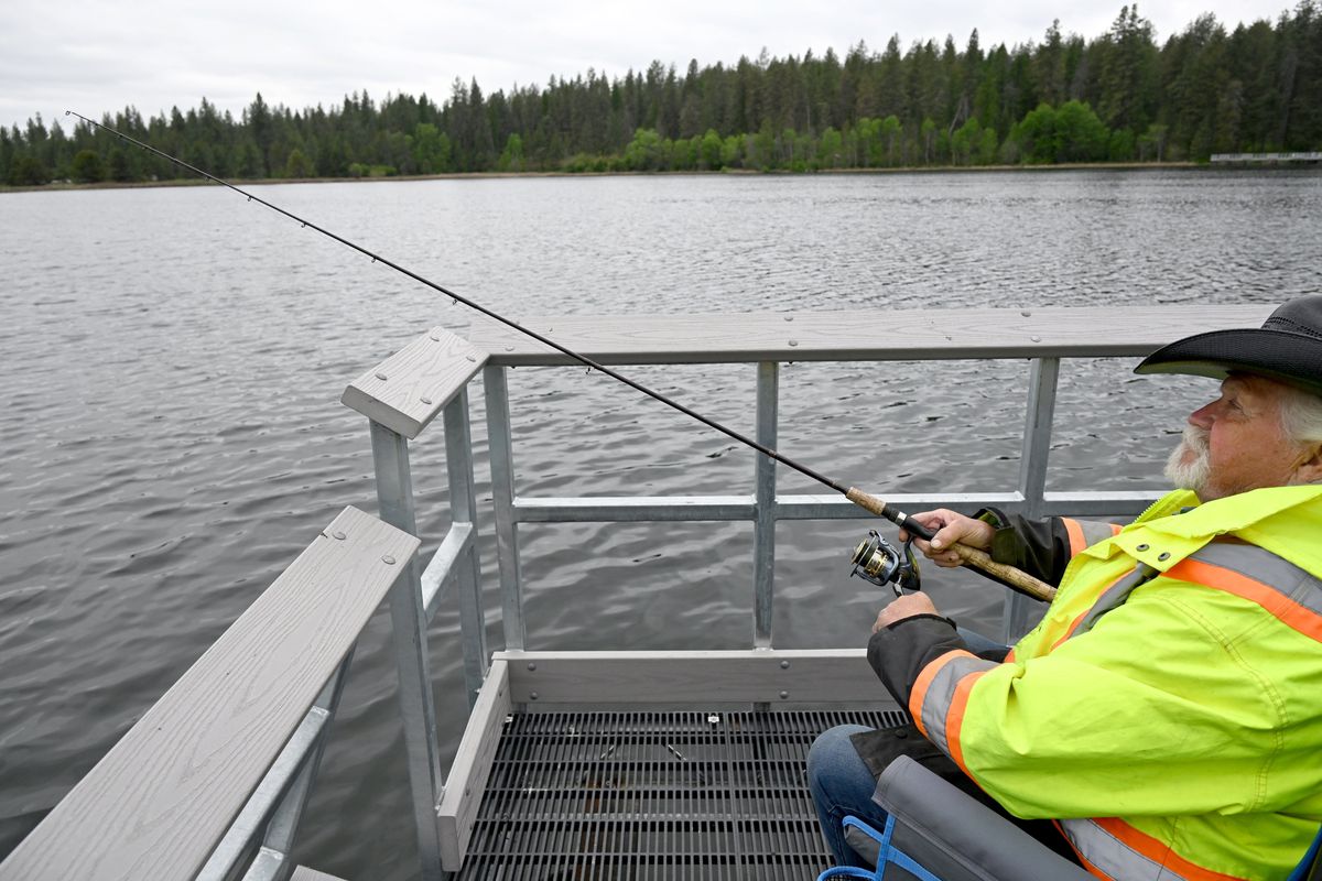Terrance Dwello fishes for trout on the ADA-accessible dock on Tuesday at Bear Lake Regional Park north of Spokane. The shallow lake just off the Newport Highway has many improvements, including a paved trail around it, fishing access points and picnic spots. (Jesse Tinsley/The Spokesman-Review)