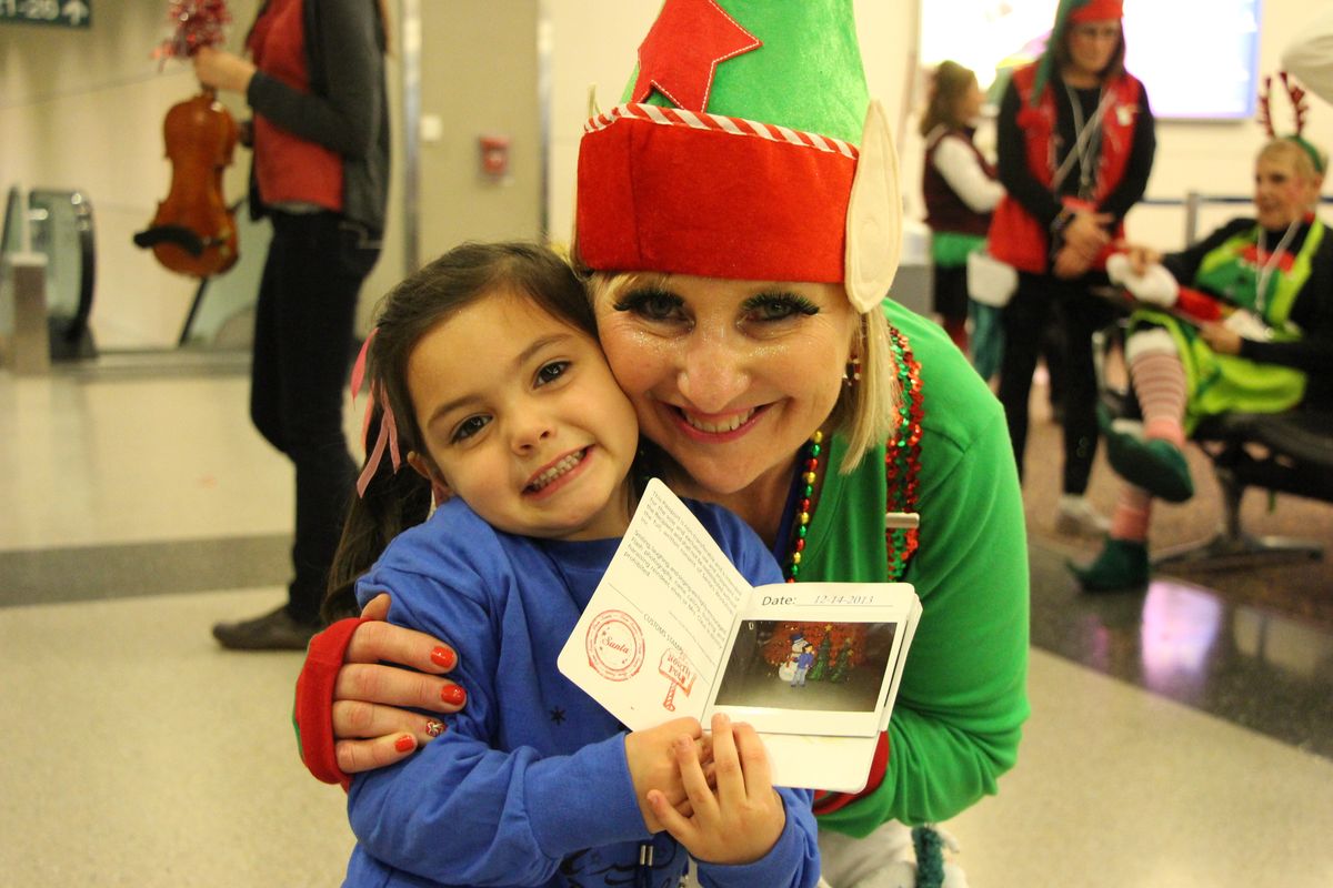 Heaven Brown, 4, is embraced by her elf, Snickerbar, during last Saturday’s Spokane Fantasy Flight at Spokane International Airport.