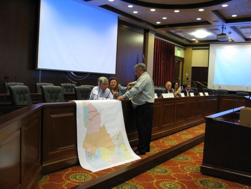 Idaho Redistricting Commission GOP Co-Chairman Evan Frasure, standing, sets up a large map showing where Republican commissioners have concerns about legislative districts that lack road connections, during a meeting on Wednesday. (Betsy Russell)