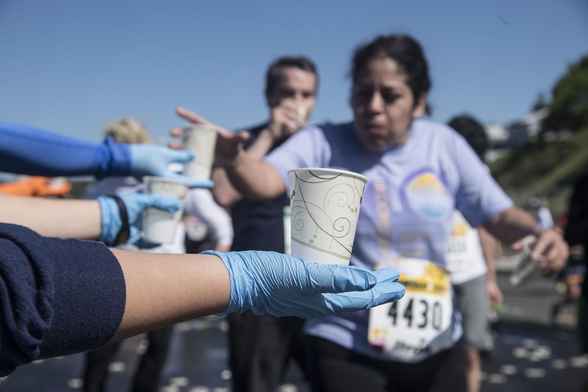 Runners should make sure to grab water during the race. (Dan Pelle / The Spokesman-Review)