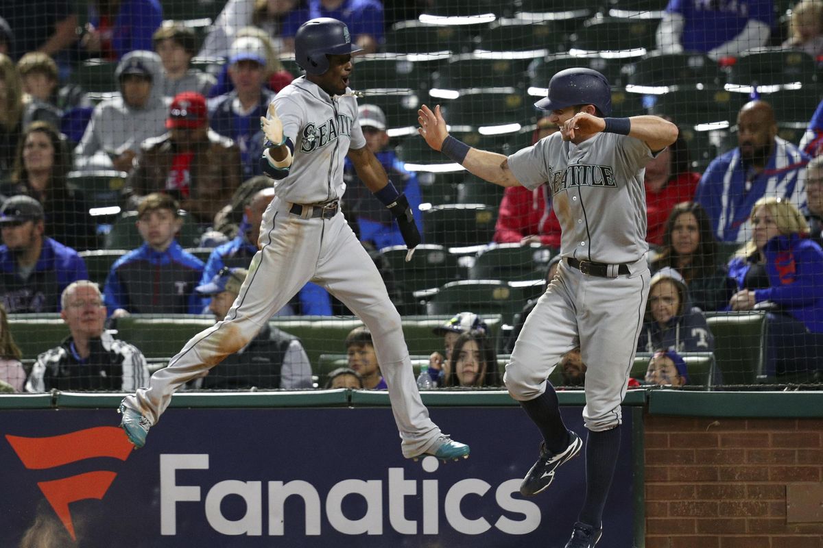 Seattle Mariners Dee Gordon, left, and Andrew Romine celebrate after they scored the go-ahead runs on a double by Jean Segura during the ninth inning of a baseball game against the Texas Rangers on Friday, April 20, 2018, in Arlington, Texas. (Richard W. Rodriguez / Associated Press)