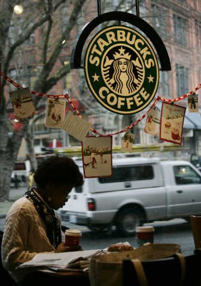 
A woman sits at a Starbucks store in downtown Seattle in December. The Seattle-based company reported earnings growth of less than 2 percent. 
 (Associated Press / The Spokesman-Review)