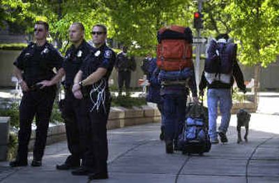 
Spokane police officers watch as campers depart the medians of Riverside Avenue on Thursday morning where they had set up a camp to protest the city's new transient camping law. 
 (Jed Conklin / The Spokesman-Review)