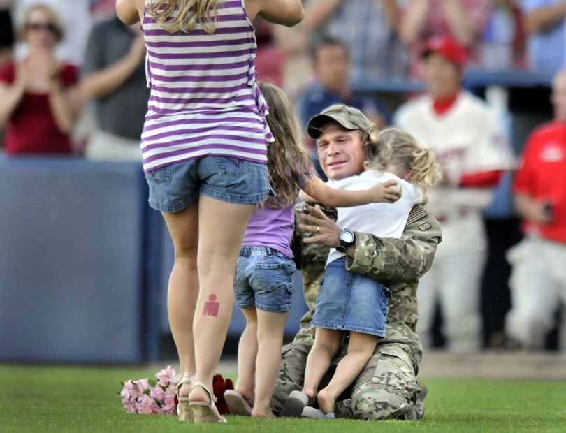Sgt. Chris Weichman hugs his twin 4-year-old girls Gracie, left, and Ruby on Monday at Avista Stadium. (Christopher Anderson)
