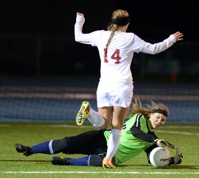 Mt. Spokane goalkeeper Shannon McReynolds slides to make a save with University’s Sarah Melvin on the attack. (Jesse Tinsley)