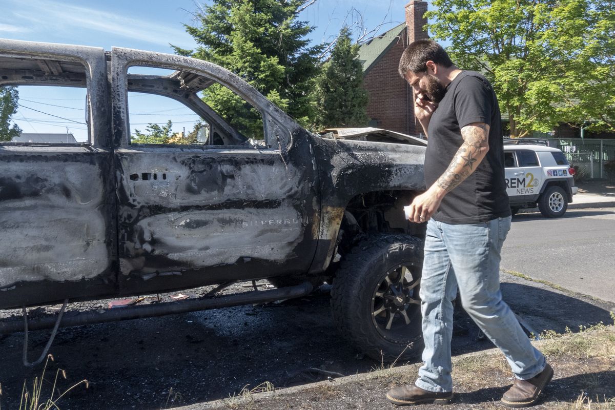 Kody Vining walks past his burned out 2008 Silverado pickup Monday while calling the Spokane Police about the incident on Crown Avenue near Division Street. Several cars were intentionally torched by unknown persons early in the morning.  (JESSE TINSLEY)