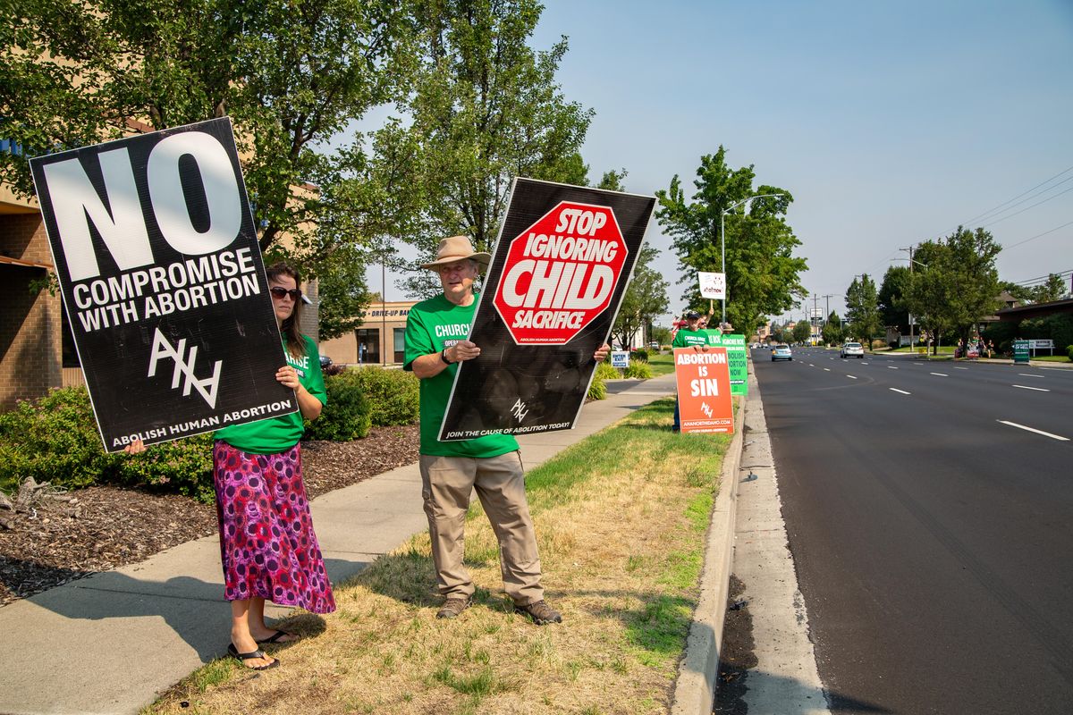 Yvonne Fredericks, left, and Rob Chase hold signs at Operation Save Spokane at the corner of Indiana on the morning of Aug. 11, 2018. The group brought together 60 or so demonstrators. (Libby Kamrowski / The Spokesman-Review)