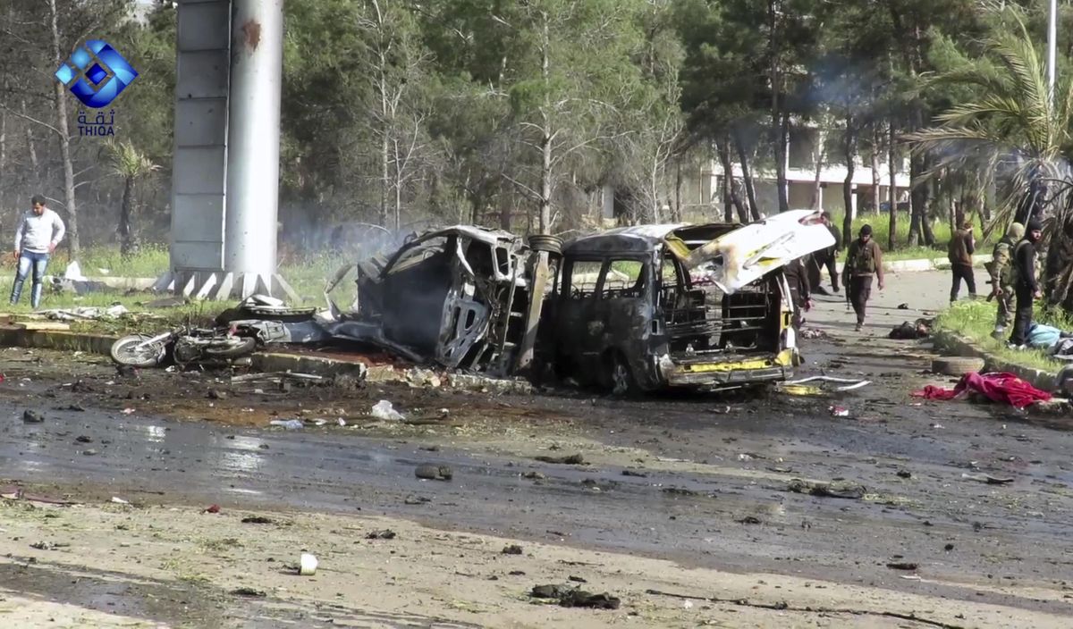 This frame grab from video provided by the Thiqa News Agency, shows rebel gunmen at the site of a blast that damaged several buses and vans at the Rashideen area, a rebel-controlled district outside Aleppo city, Syria, Saturday. (Uncredited / Associated Press)