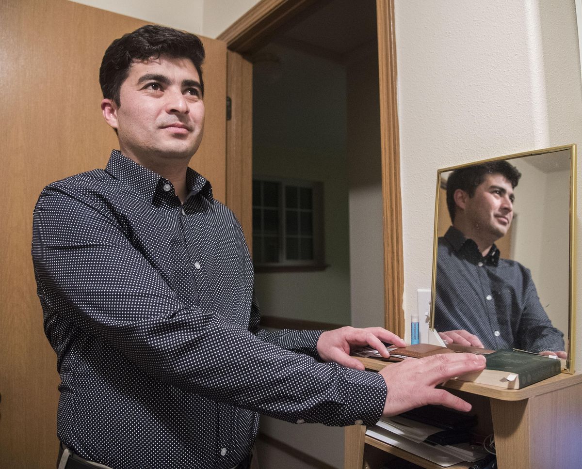 Muhammad Wahidi came to the United States two years ago from the Logar Province in Afghanistan. He is now an Eastern Washington University student and works in Liberty Lake. Here, he holds his hand over the Koran and also reads from the Bible. (Dan Pelle / The Spokesman-Review)