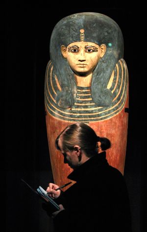 A visitor takes notes while standing in front of the inner coffin of Queen Meritamun during a preview of the King Tut exhibit Wednesday in Seattle. (Associated Press)