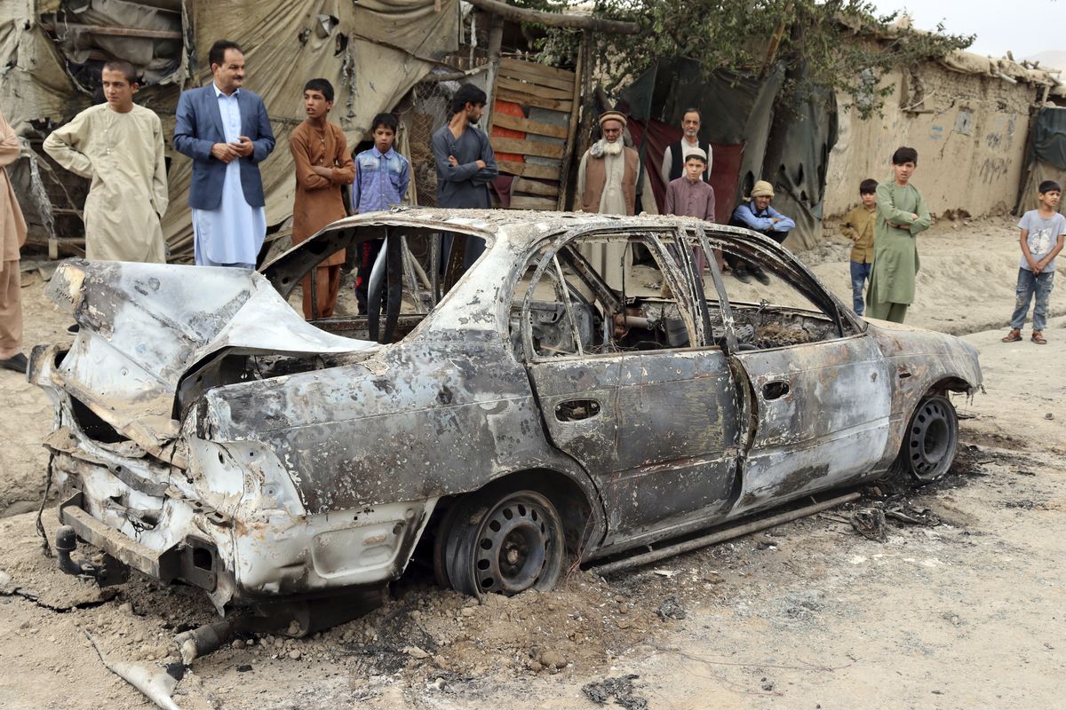 Locals view a vehicle damaged by a rocket attack in Kabul, Afghanistan, Monday, Aug. 30, 2021. Rockets struck a neighborhood near Kabul