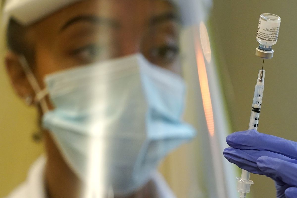 A pharmacist prepares a syringe of the Pfizer vaccine for COVID-19 on Jan. 8 at Queen Anne Healthcare, a skilled nursing and rehabilitation facility in Seattle.  (Ted S. Warren)
