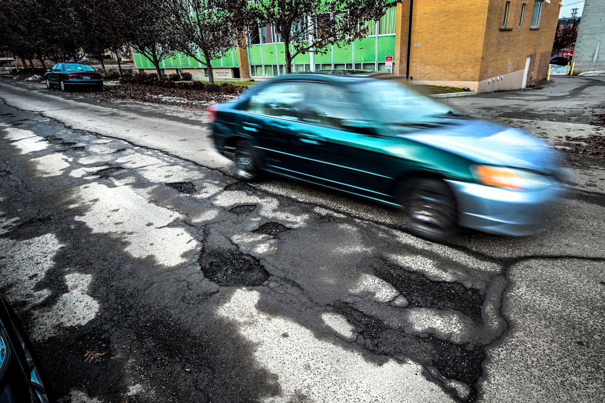 A car drives along a pothole-laden street in the 400 block of West Seventh Avenue on Jan. 20, 2023 in Spokane.  (COLIN MULVANY/THE SPOKESMAN-REVIEW)