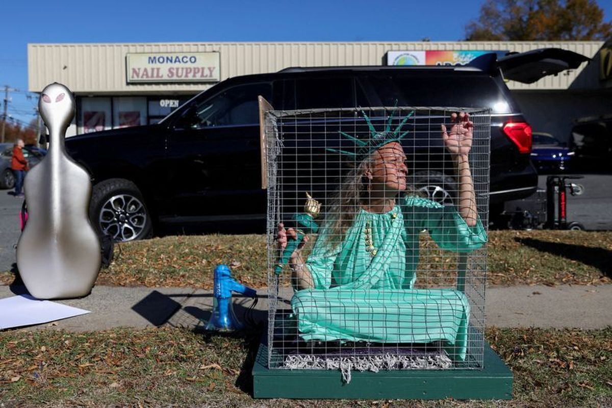 Shana Blake, a protestor wearing a Statue of Liberty outfit sits in a cage, as Members of the Customs and Border Patrol (CBP) conduct immigration raids on the streets of Charlotte, North Carolina, U.S., November 17, 2025. REUTERS/Sam Wolfe (Sam Wolfe)