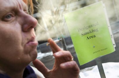 
Since the new Washington Clean Indoor Air Act went into effect Thursday, Cherlena Collins  takes her cigarette break on the east side of the STA Plaza. Signs warn smokers that they need to be 25 feet away  before lighting up. 
 (Colin Mulvany / The Spokesman-Review)