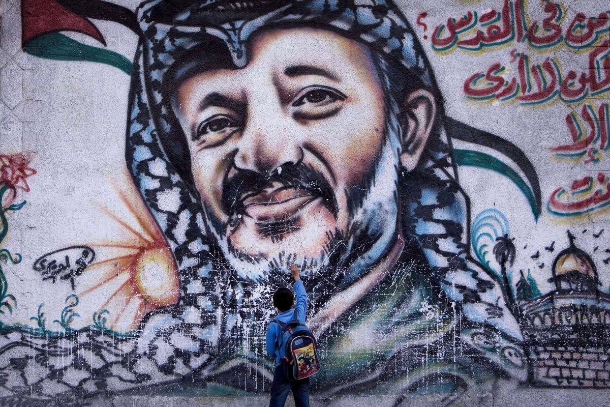 FILE - In this Nov. 10, 2009 file photograph, a Palestinian boy touches a mural of the late leader Yasser Arafat, in Gaza City. French judges will visit the West Bank town of Ramallah as part of a probe into the death of Yasser Arafat, the widow of the late Palestinian leader said Wednesday, Sept. 5, 2012. Arafat died eight years ago in a French military hospital from a stroke, but the underlying causes of the illness that preceded his death have never been determinedWriting in Arabic reads "In Jerusalem - who is in Jerusalem - I only see you". (Tara Todras-whitehill / Associated Press)