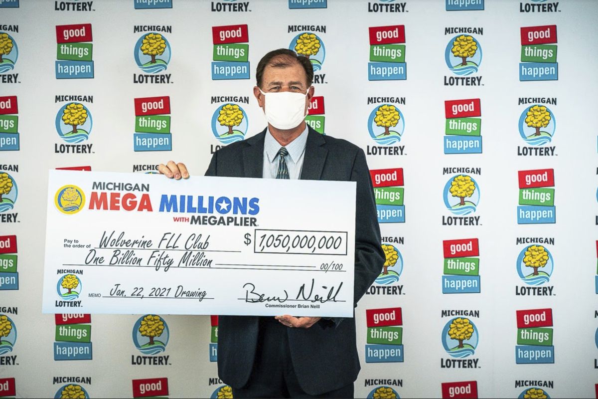 In this Feb. 26, 2021, photo provided by the Michigan Lottery, attorney Kurt Panouses poses with a check on behalf of the winners of a Mega Millions lottery jackpot in Lansing, Mich. Four people in a suburban Detroit lottery club have won a $1.05 billion Mega Millions lottery jackpot and will share $557 million after taxes. Officials made the announcement Friday, March 12, 2021, nearly two months after the Jan. 22, drawing.  (HOGP)