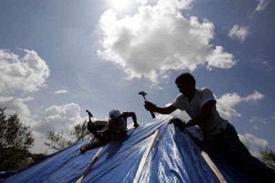
Construction workers hammer fasteners for a blue tarp on a roof top of a damaged home in the Garden District of New Orleans on Wednesday. With hundreds or even thousands of builders wiped out by the storm, their tools lost, their labor pool scattered, homeowners who hope to rebuild quickly in the wake of Katrina are likely in for a surprise.
 (Associated Press photos / The Spokesman-Review)