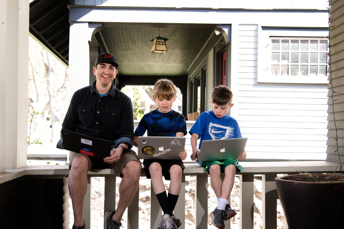 Derek Sarfino a fifth-grade teacher at Wilson Elementary, poses for a photo with his  sons Charlie, a fourth grader at Wilson, and Will, a second grader at Wilson, as they demonstrate some of the laptop-based online learning systems they use to conduct distance learning on Friday, April 17, 2020, at their home in Spokane. (Tyler Tjomsland / The Spokesman-Review)