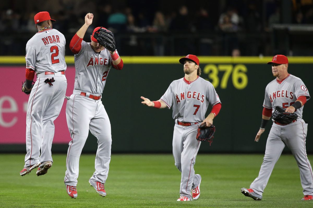 Erick Aybar and Mike Trout, center, of the Los Angeles Angels leap in celebration of Wednesday’s victory as Collin Cowgill moves in. (Associated Press)
