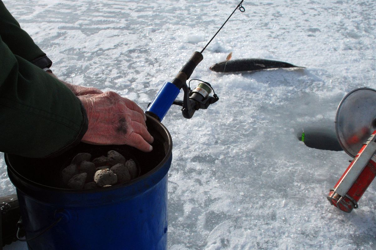 An angler warms his hands while ice fishing on Sprague Lake.  (RICH LANDERS/The Spokesman-Review)