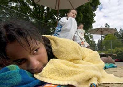 
On the first day of the Spokane city pools being open, a chilled Jamika Williams, 11, wrapped in her towel, tries to get warm before heading back into the water Monday. 
 (Colin Mulvany / The Spokesman-Review)
