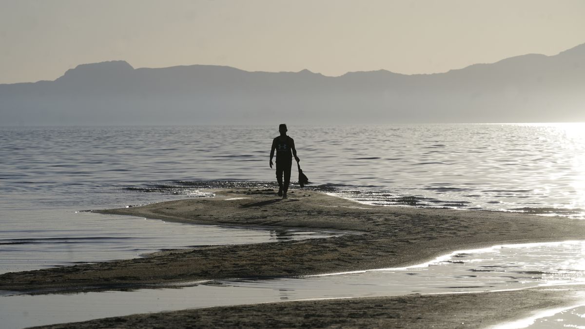 A man walks along a sand bar at the receding edge of the Great Salt Lake on June 13, 2021, near Salt Lake City. The lake has been shrinking for years, and a drought gripping the American West could make this year the worst yet. The receding water is already affecting nesting pelicans that are among millions of birds dependent on the largest natural lake west of the Mississippi River.  (Rick Bowmer)