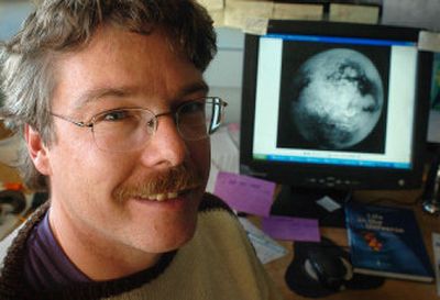 
Professor Dirk Schulze-Makuch poses with a photo of Saturn's moon Titan in his Washington State University office earlier this month in Pullman. Schulze-Makuch says the first extraterrestrial life found is likely to be single-cell organisms surviving in a moon of Saturn, or the atmosphere of Venus. 
 (Associated Press / The Spokesman-Review)