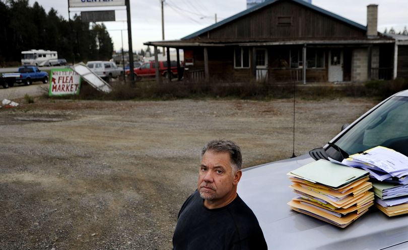 Developer Alan Johnson stands with stacks of documents from a lawsuit against him at the intersection of highways 95 and 54 in Athol. A fight with the Idaho Transportation Department has held up development of a travel center, grocery store and hotel on the site. (Kathy Plonka)