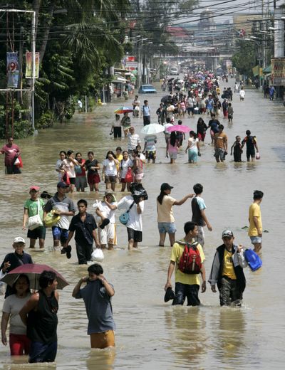 Residents wade through floodwaters as they go on with their daily business at Dagupan city, north of Manila, Philippines, on Saturday. The Philippines are reeling from back-to-back storms that dumped record rains.  (Associated Press / The Spokesman-Review)